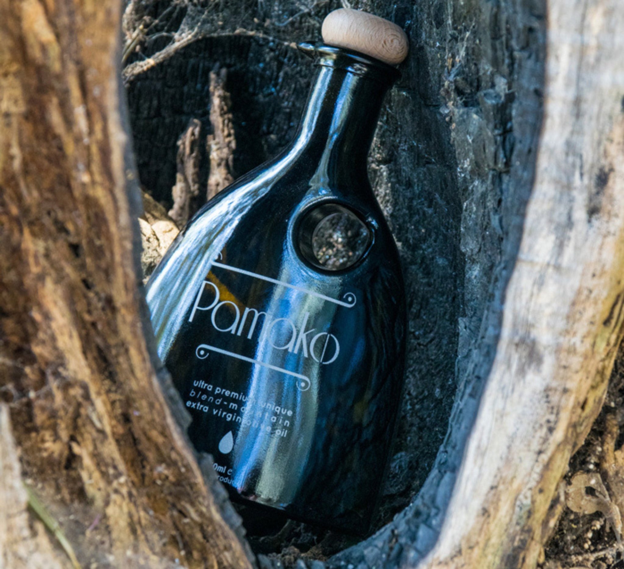 Elegant black murano bottle Pamako Blend EVOO in a wood.